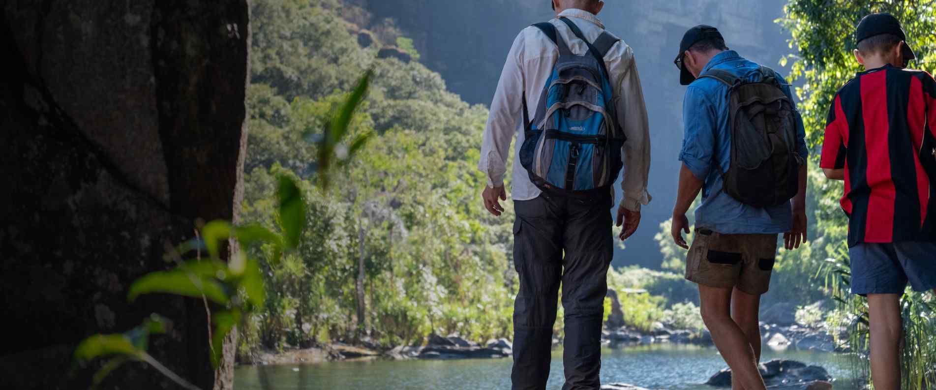 men standing next to river with daypacks on